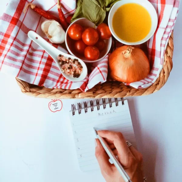 Charting your course to success with our 12-week nutrition weight loss program! This image captures the essence of preparation as someone meticulously writes a shopping list beside a basket overflowing with wholesome foods. Every item is a step towards your goals, ensuring your journey is fuelled by the best ingredients. Let's take the first step together towards a healthier you! 